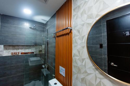 a bathroom with a shower and a round mirror at Rockfort Hotel in Cotabato