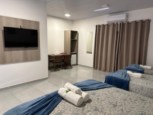 a hotel room with two beds and a flat screen tv at POUSADA ACONCHEGO MT in Chapada dos Guimarães