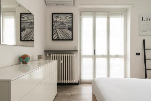a white bedroom with a bed and a dresser at Nuovo appartamento vicino Fondazione Prada in Milan