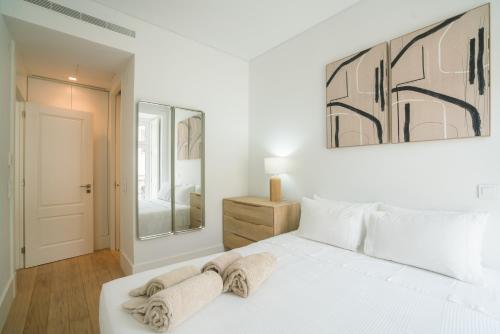 a white bedroom with a bed and a mirror at Luxury condo in heart of Baixa-Chiado in Lisbon