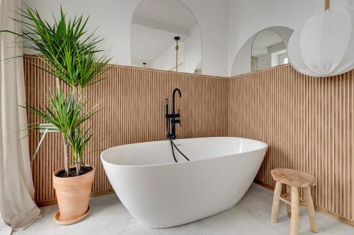 a bathroom with a white tub and two plants at Przypływ by Grand Apartments in Gdynia