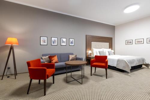 a bedroom with a bed and a couch and chairs at Hotel Ikona in Prague