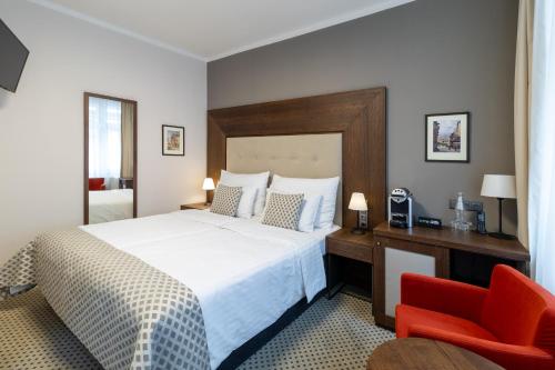 a bedroom with a large bed and a red chair at Hotel Ikona in Prague