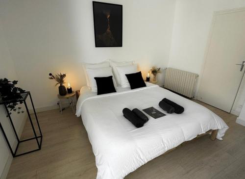 Una cama blanca con dos almohadas negras. en Lava Studio en Poitiers
