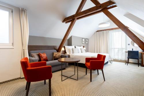 a bedroom with a bed and a couch and a table at Hotel Ikona in Prague