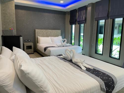 two beds in a bedroom with two rabbits on them at Hideaway Resort Banchang in Ban Chang