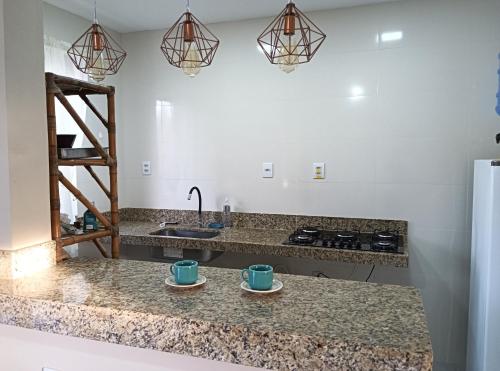 een keuken met twee kopjes op een aanrecht bij Casa - Luxo e Conforto, Hidromassagem a 50m do Mar in São Mateus