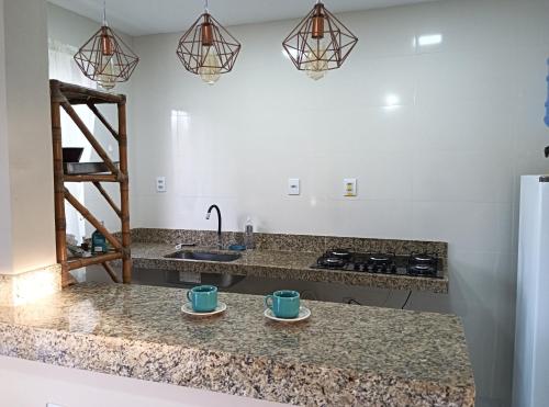 una cucina con due tazze sul bancone di Casa Tartaruga 1 - Luxo com Hidromassagem a 50m do Mar a Guriri