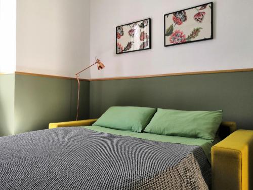 a bed in a bedroom with two pictures on the wall at Central Apartment with Panoramic Terrace in Catania