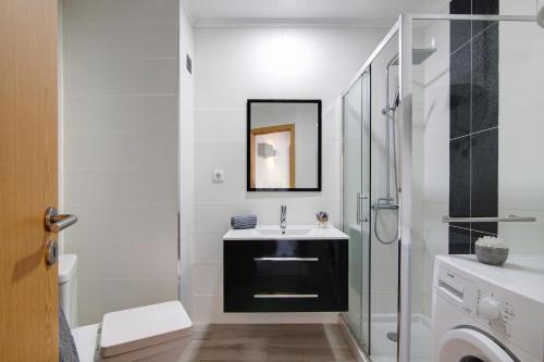 La salle de bains blanche est pourvue d'un lavabo et d'une douche. dans l'établissement Apartamento da Rocha I, à Portimão