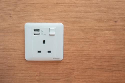 a white electrical outlet on a wooden table at Ipoh Tambun Sunway Onsen Suite 3R2B Maya in Tambun