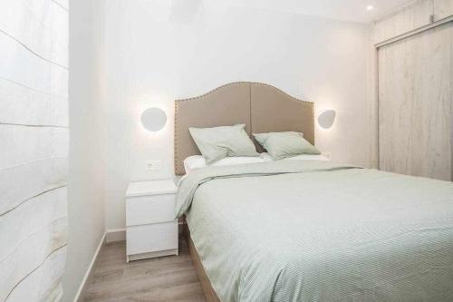 een witte slaapkamer met een bed en een nachtkastje bij Apartamento Arresi Deluxe in Bermeo
