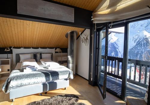 a bedroom with a bed and a view of mountains at Lauchernalp Resort Residences in Wiler