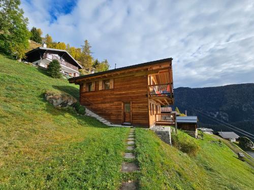 a wooden building on a grassy hill with a house at Müelera in Blatten bei Naters