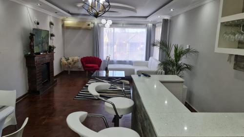 a living room with a bar with white stools at Suprime Hotels and Conference in Pietermaritzburg