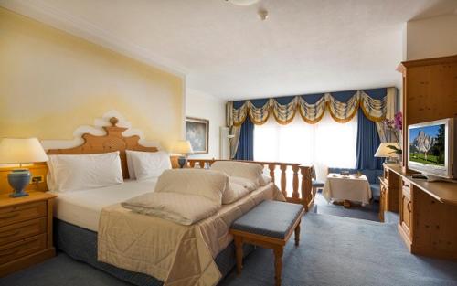 a bedroom with a large bed and a television at Hotel Sassongher in Corvara in Badia