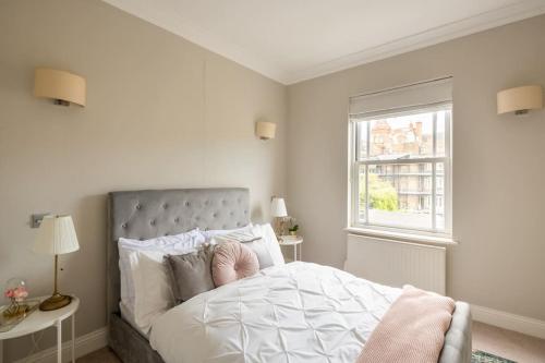 a bedroom with a large white bed with a window at Beaufort Gardens Apartment in Knightsbridge in London