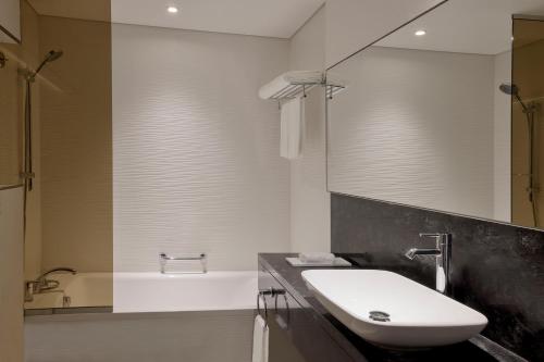 La salle de bains est pourvue d'un lavabo, d'une baignoire et d'un miroir. dans l'établissement The First Collection Waterfront, à Dubaï