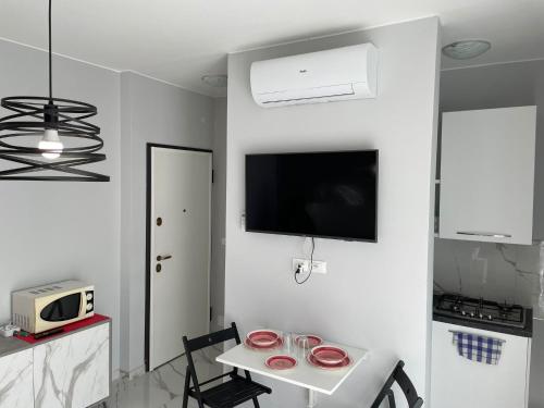eine weiße Küche mit einem Tisch und einem TV an der Wand in der Unterkunft Cuore e Sole - Attico Monolocale con Parcheggio Privato A 5 minuti dal centro in Sanremo