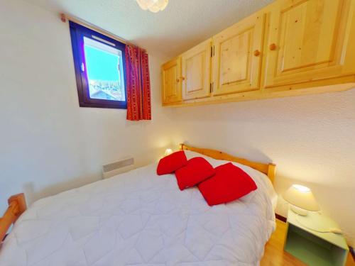 une chambre avec un lit blanc avec des oreillers rouges dans l'établissement Charmant 2 pièces aux Saisies, 3ème étage, 4 pers., proche centre, balcon sud/est, ski facile! - FR-1-594-125, à Hauteluce