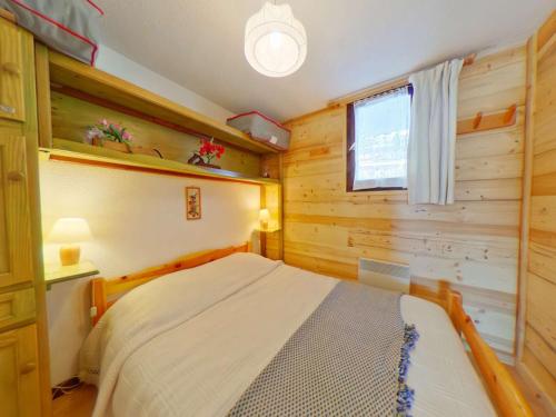 une chambre avec un lit dans une pièce aux murs en bois dans l'établissement Les Saisies : 2 pièces pour 4 pers, centre station - FR-1-594-149, à Hauteluce