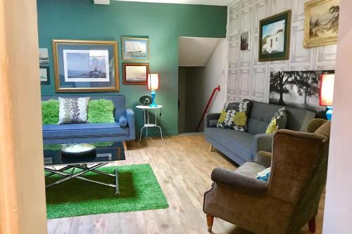 a living room with a blue couch and a green wall at higgihaus #107 Sleeps up to 22 Hens Stags Rugby in Cardiff