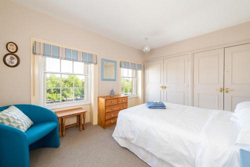 a bedroom with a bed and a chair and windows at Stunning & spacious Georgian town house in St Neots town centre with parking in Saint Neots