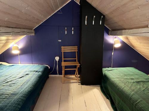 1 dormitorio con 2 camas y silla de madera en Cozy cottage with its own bathing cliff located at Odensvi en Odensvi