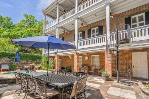 a table with a blue umbrella in front of a house at Hamilton Suite 1 - Ground Floor, Courtyard in Savannah