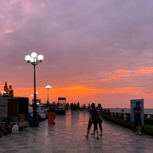 a group of people walking on a pier at sunset at Khanh Linh Hotel in Vung Tau