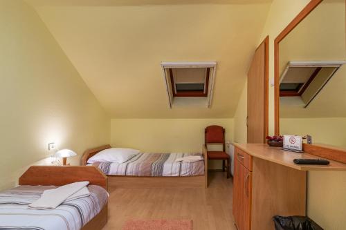 a small room with two beds and a desk with a desk at Kisduna Étterem-Panzió in Dunaharaszti