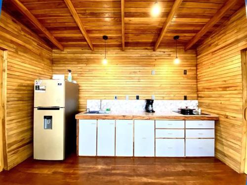 cocina con nevera y paredes de madera en Hoja Azul - Sustainable teak modern cabin in Hojancha, en Hojancha