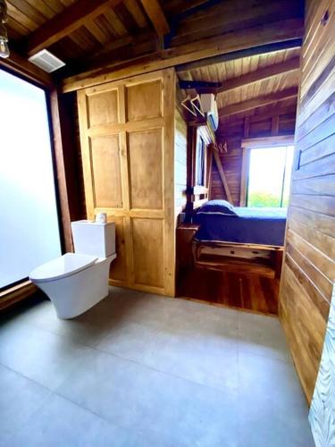 a bathroom with a toilet and a bed in a room at Hoja Azul - Sustainable teak modern cabin in Hojancha in Hojancha