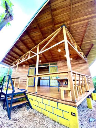a house with a wooden roof with a table and a bench at Hoja Azul - Sustainable teak modern cabin in Hojancha in Hojancha