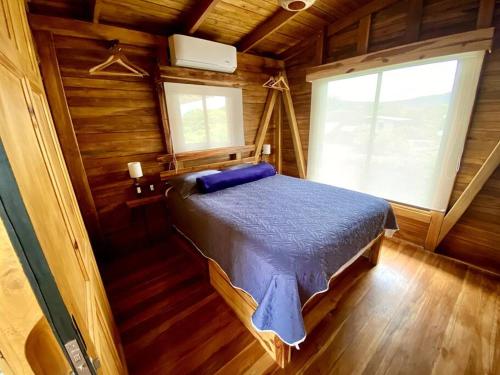 a bedroom with a bed in a wooden cabin at Hoja Azul - Sustainable teak modern cabin in Hojancha in Hojancha