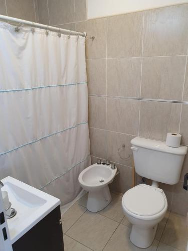 a bathroom with a toilet and a shower curtain at Depto.céntrico, confortable dos ambientes y óptima ubicación. in Viedma