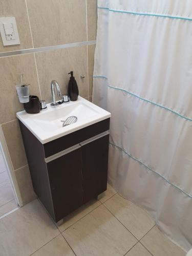 a bathroom with a sink and a shower curtain at Depto.céntrico, confortable dos ambientes y óptima ubicación. in Viedma