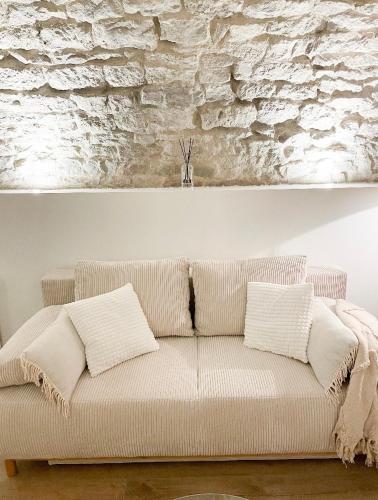 a white couch in a room with a stone wall at La voute Doloise - Love room & spa in Dole