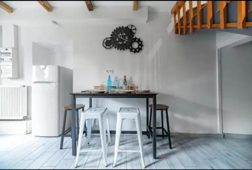 a kitchen with a table with stools and a refrigerator at ⟬La Maisonnette de Séverine⟭ in Saint-Genès-Champanelle