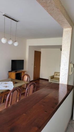 una sala de estar con una gran mesa de madera y sillas en Neuquén Center Apartamentos en Neuquén