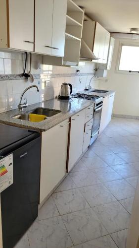 a kitchen with white cabinets and a sink at Neuquén Center Apartamentos in Neuquén