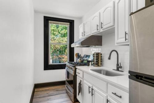 a kitchen with white cabinets and a sink and a window at Charming 2BR Philadelphia Retreat with Free Parking in Philadelphia