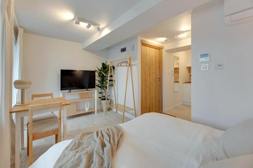 Schlafzimmer mit einem Bett, einem Schreibtisch und einem TV in der Unterkunft Kamień by Grand Apartments in Gdynia