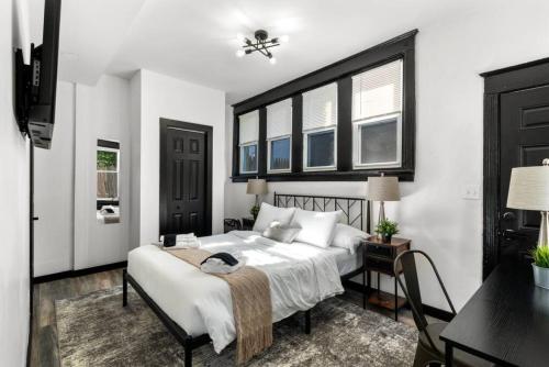 a bedroom with a bed and a desk and windows at Stylish 3BR Philly Retreat with Free Parking in Philadelphia