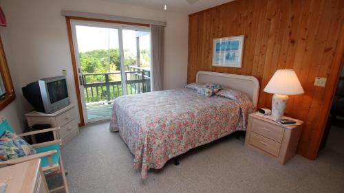 Un dormitorio con una cama y un televisor y un balcón. en Oceanside, 6 BRs, Private Pool, Ocean Views, Foosball, O2, Topside, en Duck