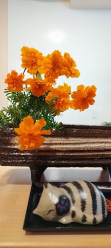 a vase filled with orange flowers next to a plate at Inari-Home in Kyoto