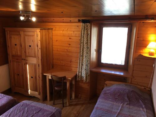 une chambre avec deux lits et une table et une fenêtre dans l'établissement Chalet pour 6/7 pers. proche centre avec cuisine équipée - FR-1-467-66, au Grand-Bornand