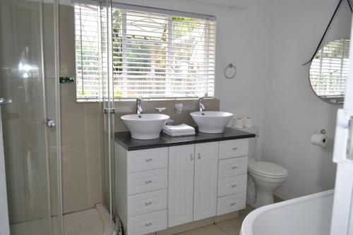 a white bathroom with two sinks and a shower at Bryanston Elgin - Cottage 3 in Johannesburg