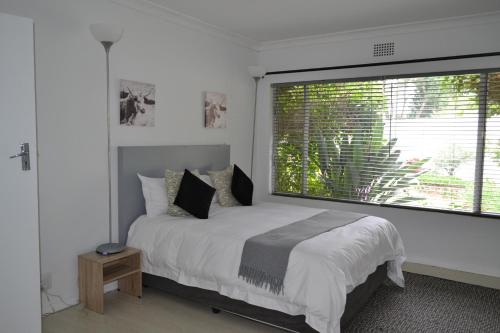 a bedroom with a bed and a large window at Bryanston Elgin - Cottage 3 in Johannesburg