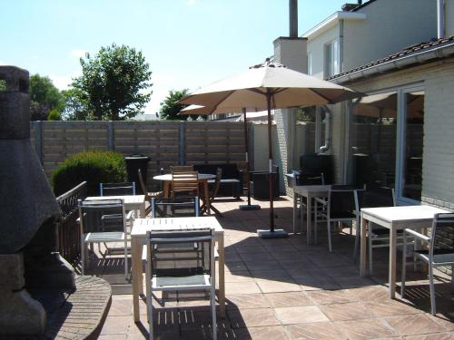 a patio with tables and chairs and an umbrella at B&B De Kleine Prins in Middelkerke